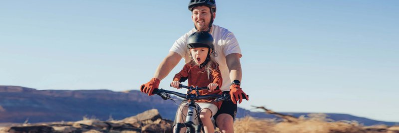 Das Foto zeigt Vater und Sohn auf einem Mountainbike mit Kids Ride Shotgun Kindersitz während der Fahrt.